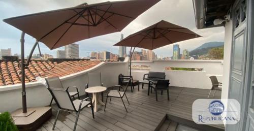 a patio with chairs and tables and umbrellas on a roof at REPUBLICANA CASA HOSTAL - HABITACION 1 QUIMBAYA in Bogotá