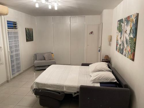ein Schlafzimmer mit einem Bett und einem Stuhl darin in der Unterkunft Sunny cottage, belle terrasse, proche et vue mer in Sainte-Luce