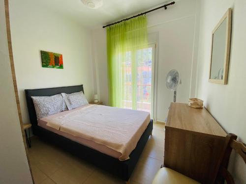 a bedroom with a bed with a green curtain and a window at Chrisa's Guest House in Skala Potamias