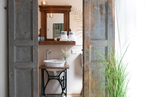 Une vieille porte s'ouvre sur une salle de bains pourvue d'un lavabo. dans l'établissement Donna Elena - Epoque Residence, à Asti