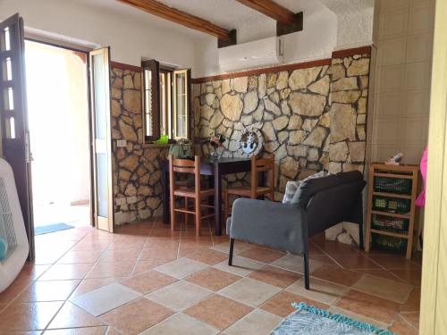 sala de estar con mesa y pared de piedra en Filumare, en Marina di Fuscaldo
