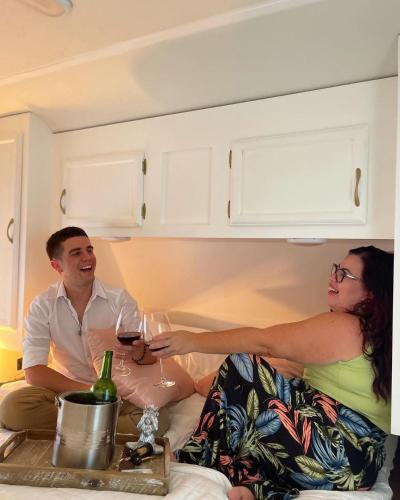 a man and woman sitting on a couch holding wine glasses at El Camper RV with pool. in Aguadilla