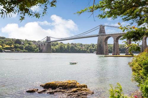 a bridge over a river with a boat in the water at The Art Deco House in Menai Bridge