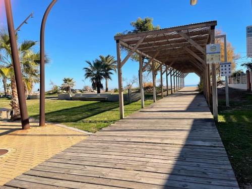 una passerella di legno che conduce a una spiaggia con palme di Precioso apartamento con piscina en Moncofar a Moncófar