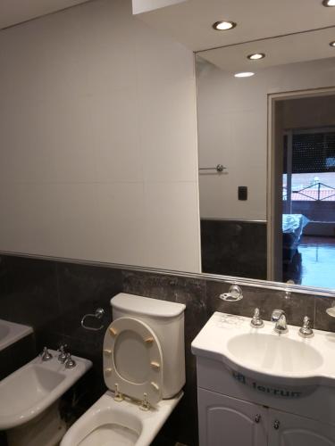 a bathroom with a toilet and a sink and a mirror at depto salta dean funes in Salta
