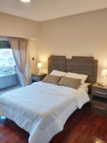 a bedroom with a large white bed with two night stands at depto salta dean funes in Salta