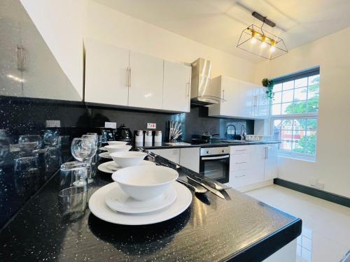 a kitchen with white cabinets and white bowls on a counter at YO ROOM! Apartments- Next to City Centre Apartment - With Free Parking in Leicester