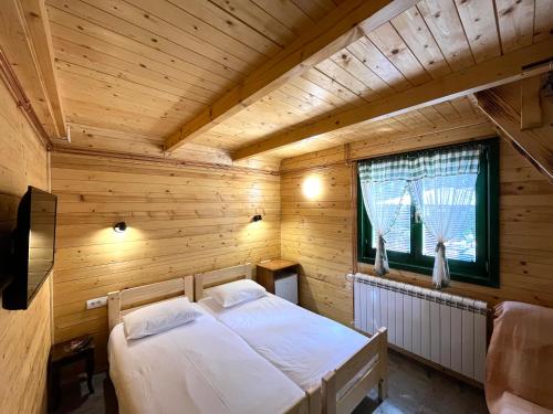 sypialnia z łóżkiem w drewnianym pokoju w obiekcie Guest House Golijski Dar w mieście Dajići