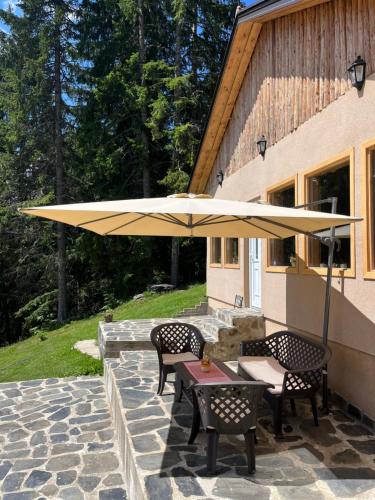 a patio with a table and chairs under an umbrella at Guest House Golijski Dar in Dajići