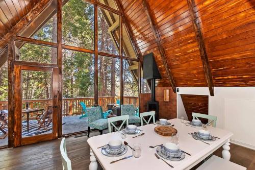 a dining room with a table and chairs and windows at Lakes Edge Lodge A-frame steps away from the lake! in Lake Arrowhead