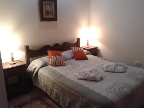 a bedroom with a bed with pillows and two lamps at Hosteria Sueños Dorados in Merlo