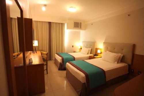 a hotel room with two beds and a television at Royal Macaé Palace Hotel in Macaé