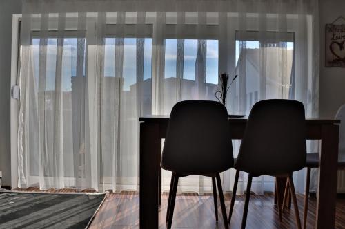 a dining room table with two chairs in front of a window at Malda's Apartment in Pristina