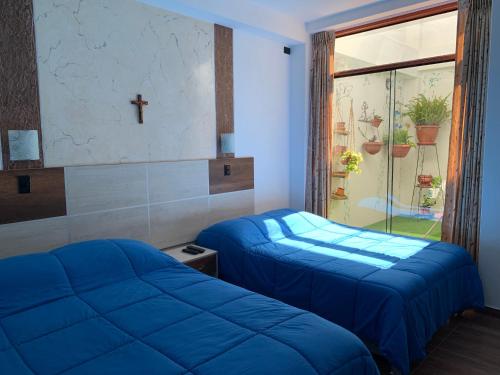 2 camas en una habitación con una cruz en la pared en Depa A - Primer Piso, en Cajamarca