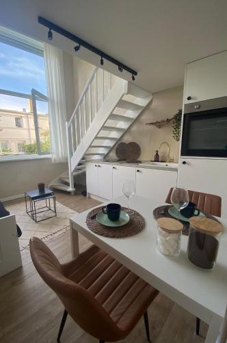 une cuisine blanche avec une table et un escalier dans l'établissement Duplex au centre de Wimereux et proche de la mer, à Wimereux