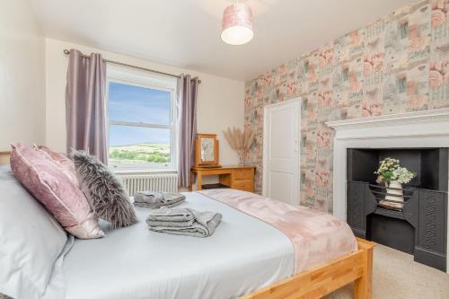 a bedroom with a bed with a fireplace and a window at Street House Farm Cottage in Saltburn-by-the-Sea