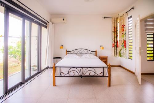 a bedroom with a bed and large windows at Villa Angelou - Sunlit Beach Getaway with Pool and WIFI in Belle Mare