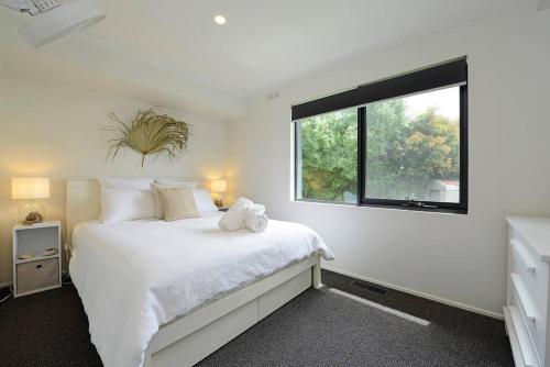 a bedroom with a white bed and a window at Salty Escape in Rosebud