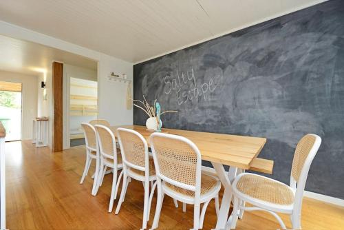 a dining room with a table and chairs and a chalkboard at Salty Escape in Rosebud