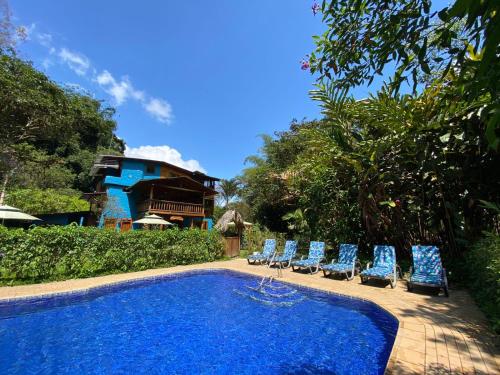 a swimming pool with chairs and a building in the background at Hotel El Abrazo del Arbol in Mindo