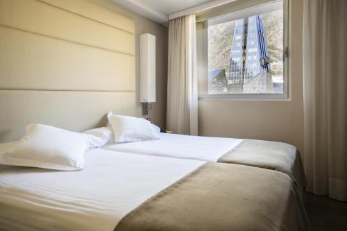 a bedroom with a large white bed with a window at Yomo Mola Park in Andorra la Vella