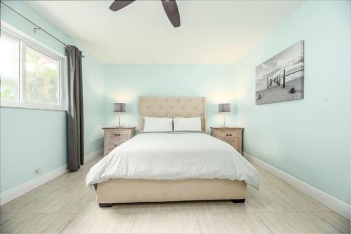 a white bedroom with a bed and two night stands at Steps to Sand and Sea 2 in Fort Lauderdale