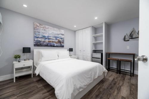 a white bedroom with a large white bed and wooden floors at Shell on the Beach 103 - RENOVATED in Hollywood