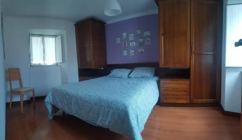 1 dormitorio con cama y pared púrpura en Casinha da Peneda en Góis