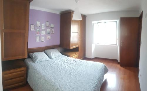 a bedroom with a bed with purple walls and a window at Casinha da Peneda in Góis