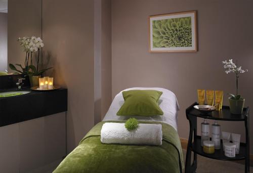 a small bedroom with a bed with a green blanket at Meon Valley Hotel, Golf & Country Club in Shedfield