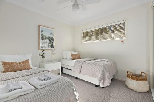 a white bedroom with two beds and a window at Rock Salt by Experience Jervis Bay in Huskisson