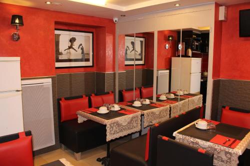 une salle à manger avec deux tables et des murs rouges dans l'établissement Hôtel des Buttes Chaumont, à Paris