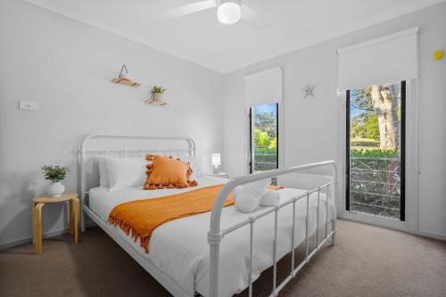 a white bedroom with a bed and a window at The Oasis of Calm by Experience Jervis Bay in Huskisson