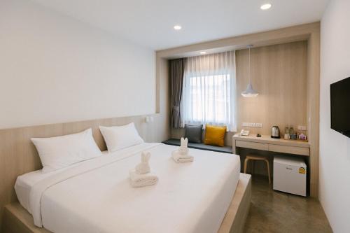 a hotel room with a white bed and a television at Nappiness Hotel - SHA ExtraPlus in Bangkok