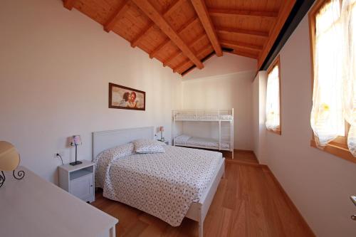 a bedroom with a white bed and a wooden floor at Agriturismo la Scala in Salò