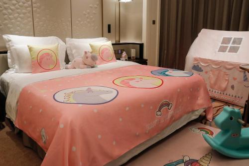 a bed with a pink blanket with stuffed animals on it at Wyndham Qingdao l Free Fixed-Time Shuttle Service Between Hotel and Airport & North Railway Station l Outdoor Children's Amusement Park l 1-Hour Play Snooker or Table Tennis in Qingdao