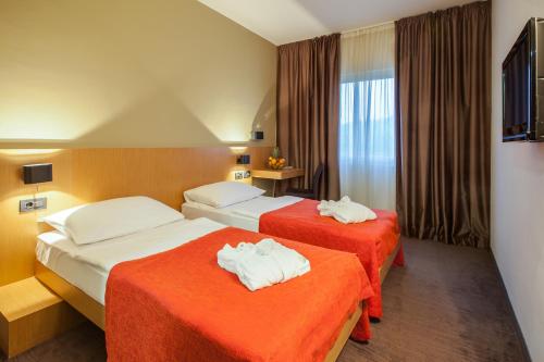 Habitación de hotel con 2 camas con sábanas de color naranja en Terme Tuhelj Hotel Well, en Tuheljske Toplice
