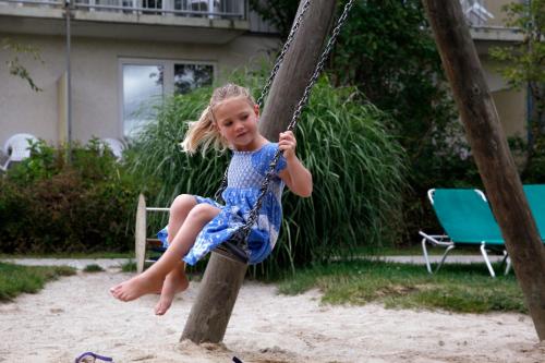 a little girl is sitting on a swing at Sonnenhotel Bayerischer Hof - All Inklusive Angebote verfügbar in Waldmünchen