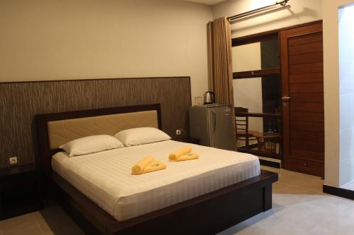 a bedroom with a bed with two yellow slippers on it at New ASTA GRAHA GUESTHOUSE in Jimbaran
