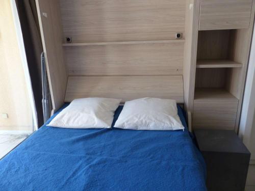 Una cama con dos almohadas encima. en Studio Le Lavandou, 1 pièce, 4 personnes - FR-1-308-152, en Le Lavandou