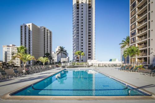 ein Schwimmbad in der Mitte einer Stadt mit hohen Gebäuden in der Unterkunft Aston at the Waikiki Banyan in Honolulu