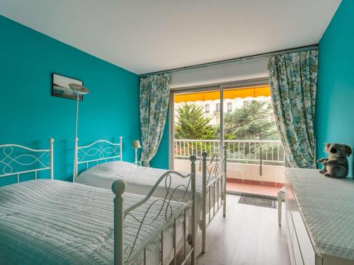 2 Betten in einem Zimmer mit blauen Wänden und einem Fenster in der Unterkunft Appartement Biarritz, 3 pièces, 4 personnes - FR-1-3-560 in Biarritz