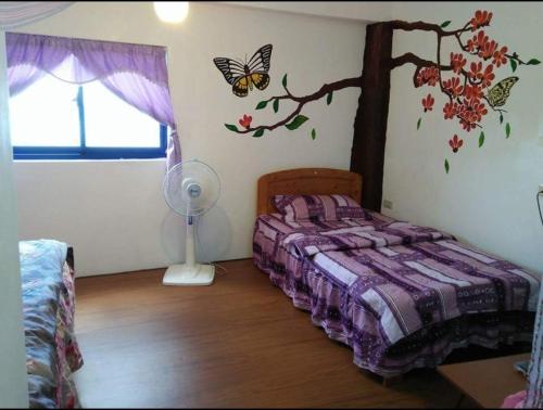 a bedroom with a bed with a tree and butterflies on the wall at Lanyu My Home B&B in Lanyu