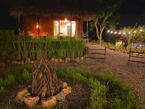 a garden with a tree stump in front of a house at Mường Sang Retreat in Mộc Châu