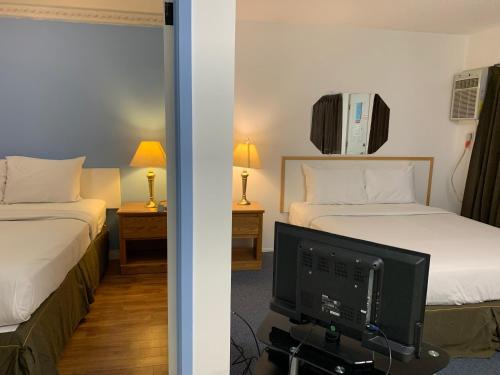 a hotel room with two beds and a television at Swiss Sunset Inn in Penticton