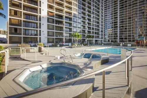 a hot tub in a patio with a large building at Aston at the Waikiki Banyan in Honolulu