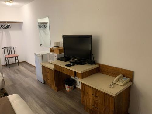 a living room with a television and a telephone at Swiss Sunset Inn in Penticton