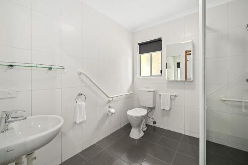 a white bathroom with a toilet and a sink at NRMA Angourie Resort, Yamba in Yamba