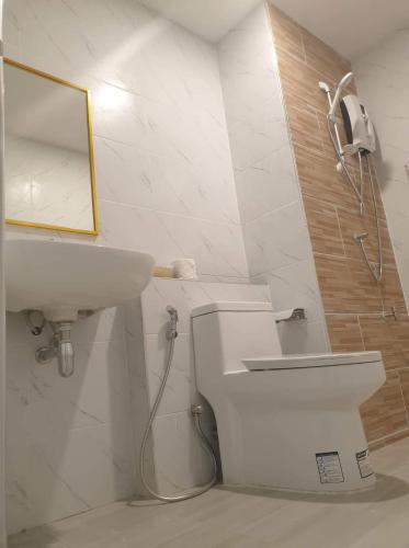 a white bathroom with a sink and a mirror at Sritrang Residence in Ban Khlong Wa