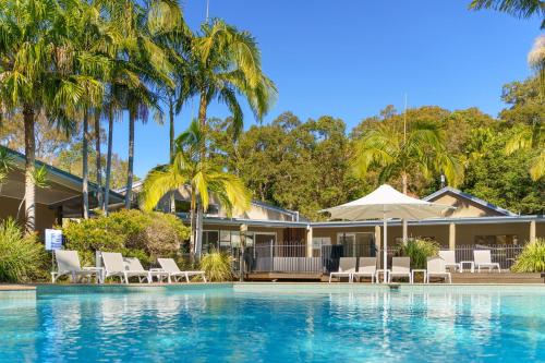 a house with a swimming pool and palm trees at NRMA Angourie Resort, Yamba in Yamba